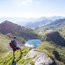 Wanderer auf Berggipfel blickt auf Bergsee und Berglandschaft